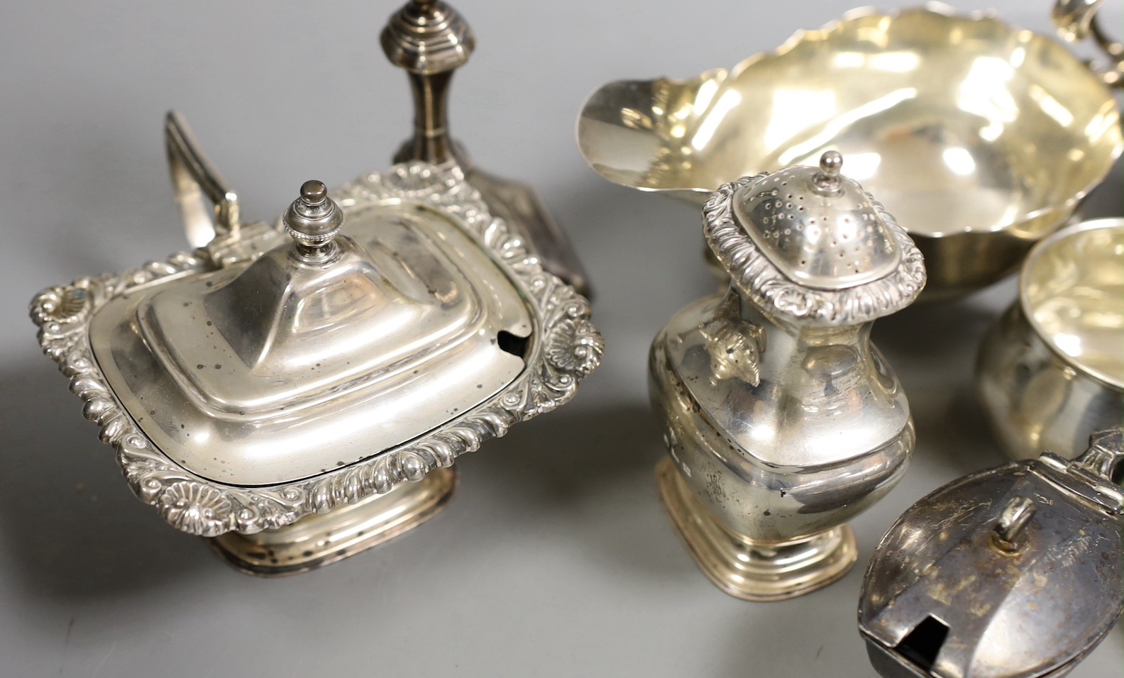 A pair of late Victorian silver sauceboats, Frederick Augustus Burridge, London, 1899, a George V silver mounted taperstick, a modern silver three piece condiment set, a silver chamberstick, silver mug, two silver small
